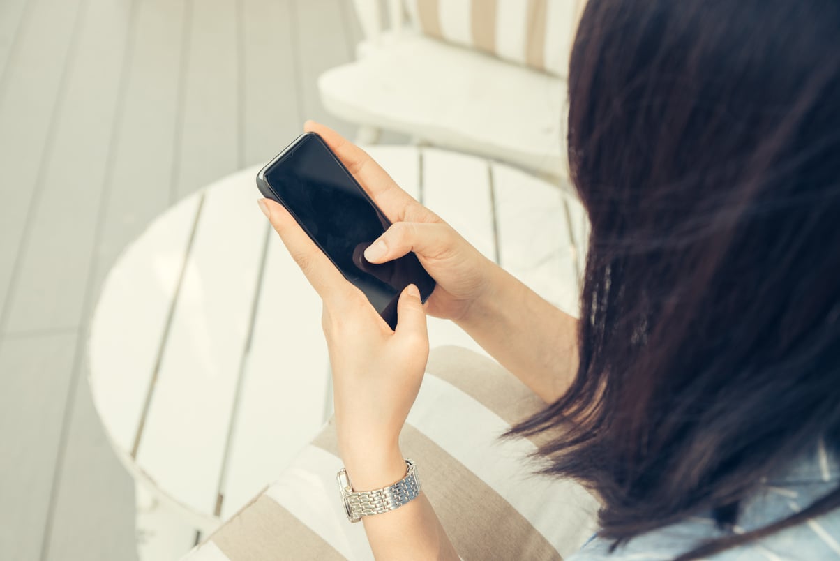 Woman Typing Text Message on Smart Phone in a Cafe. Cropped Imag